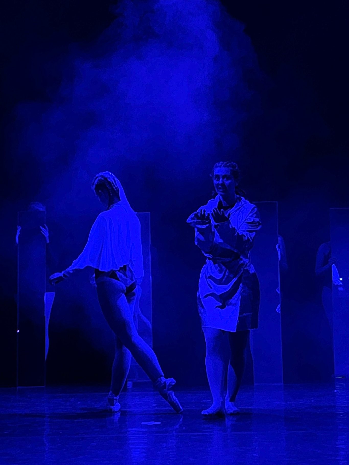Zwei Tänzer auf Bühne, blauer Nebel- und Lichtschein, dramatische Pose.