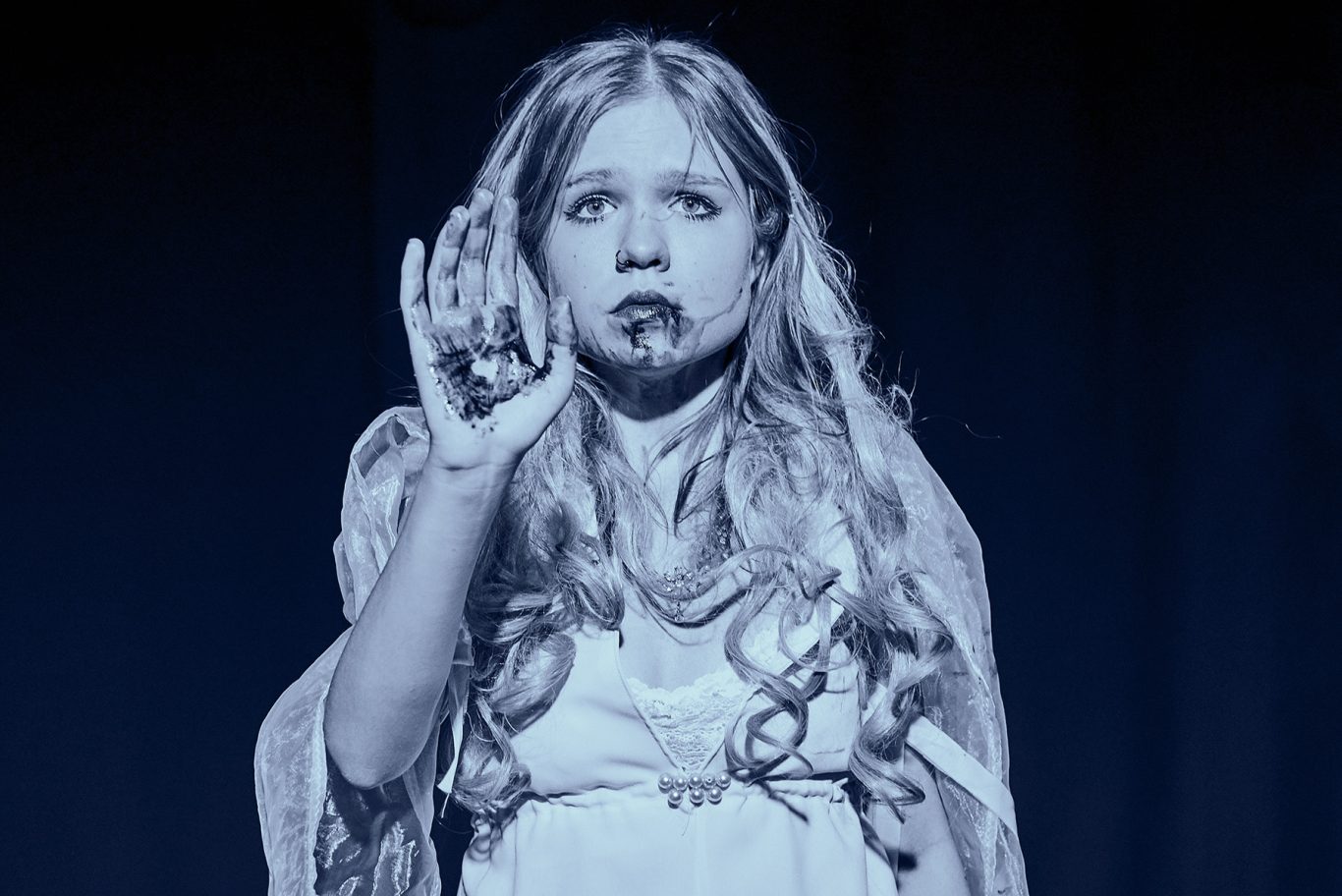 Junges Mädchen mit langem Haar, blicken nach oben, eine Hand erhoben, monochromblau.